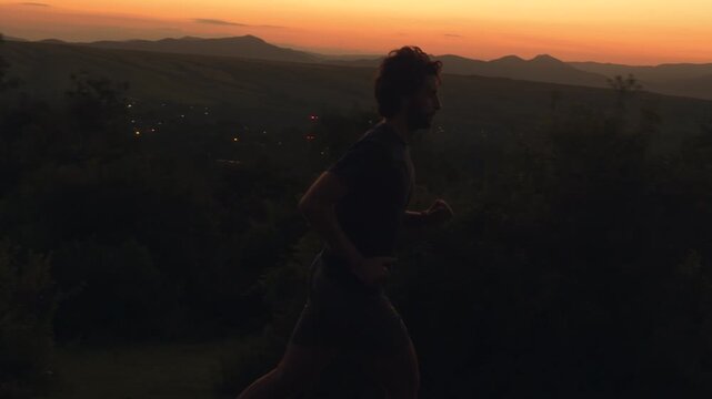 Silhouette of man running on grassy hill at golden hour sunset sunrise