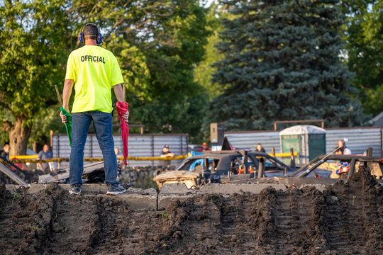 Event official stands as spectators prepare for action at a demolition derby at a local fairground in the afternoon