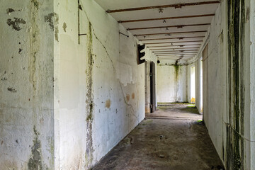 Fototapeta premium Sunlight shines through the open doors of a creepy hallway in historic Battery Ord at Fort Columbia State Park, WA, USA