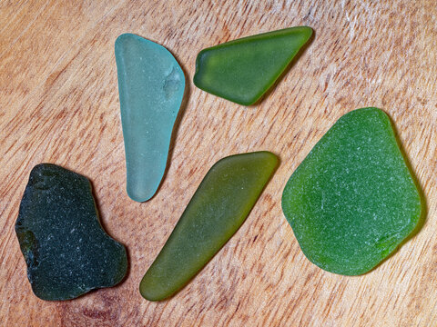 Collected pieces of colorful sea glass on a wooden surface