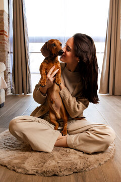 Woman showing affection to dachshund puppy at home