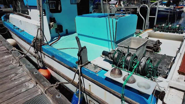 Blue fishing boat bow with anchor and rusty winch
