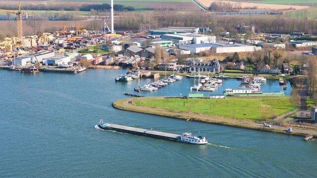 stacked materials cranes dominate quay boats rest nearby marina farmland open sky extend beyond industrial yard along canal zelzate shipping maritime zone dockyard 