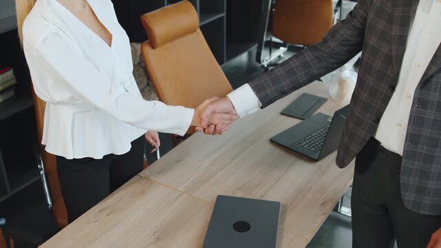 Business people shake hands in a modern office during a meeting on a weekday morning while discussing plans and projects