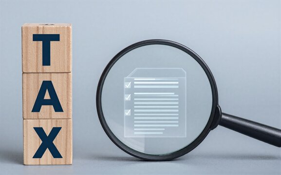 Tax blocks beside magnifying glass inspecting a checklist document.