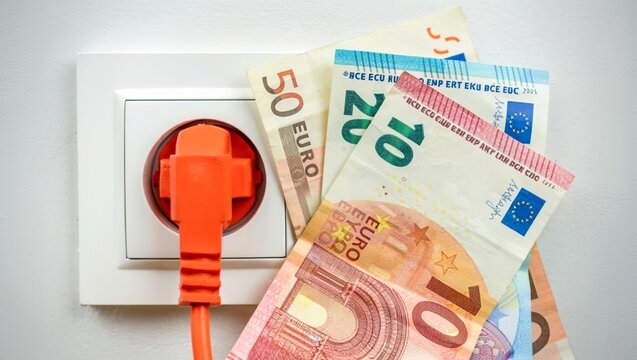 Euro banknotes placed next to an electric plug inserted into a wall socket, visually representing the rising costs of electricity and energy consumption in Europe