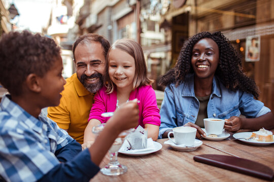 Happy family enjoying dessert at outdoor cafe in city