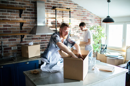 Two men unpacking boxes in new home kitchen