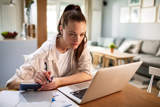 Young woman managing finances on laptop at home