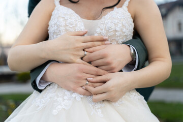 Couple hug each other while hold wedding rings.