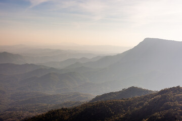 Obraz premium Mountains in Loei, Thailand. Misty morning landscape with rolling hills and fog. Layered mountain ranges with forested slopes. Sunlight breaking through clouds.