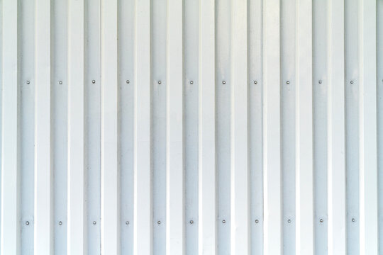 White corrugated metal texture background featuring clean vertical lines and rivets. Industrial steel siding surface ideal for construction or architectural design. High resolution wall cladding.