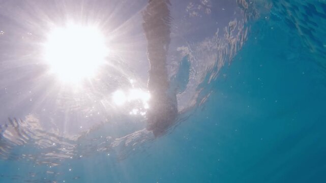 Underwater view woman reaching hand offering help to drowning person with summer sunlight reflection