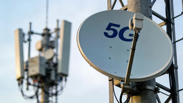 Focused medium shot of a satellite receiving dish on a cellular tower with blurred network equipment representing wireless backhaul links in 5G deployment scenarios.