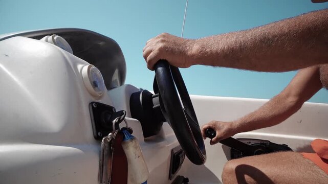 Sport man steering and controlling fast cruising yacht motorboat on sunny day on open sea