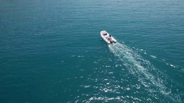 Aerial view of fisherman cruising with rubber motorboat through a blue sea in summer