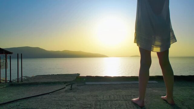 Depressed woman look at sunset view standing on balcony overlooking the tranquil sea