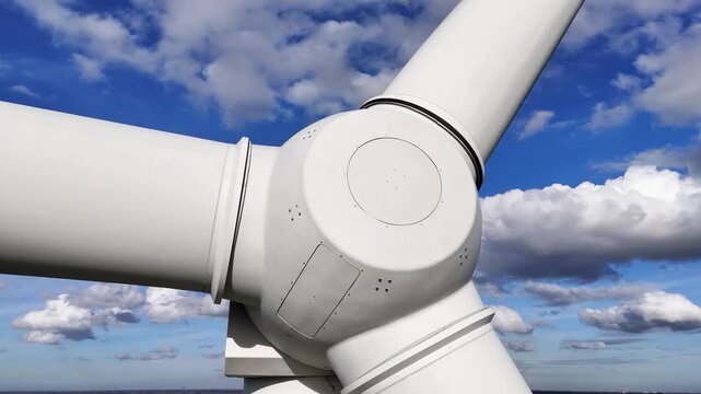 low wind turbine robust hub blades against deep blue sky textured clouds mechanical strength behind renewable electricity reveals angle view low-angle energy technology power 