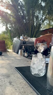 Professional bartender pouring pink cocktail through a strainer into a glass with ice. Crafting a refreshing summer drink at a luxury Arabian all-inclusive resort bar in Hurghada, Red Sea, Egypt.