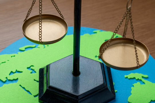 Brass scales of justice on a paper world map cutout. International law, global justice, trade equality, geopolitical diplomacy, and environmental balance concept.