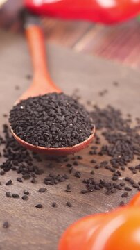 Black cumin seeds shown on a wooden spoon in kitchen setting