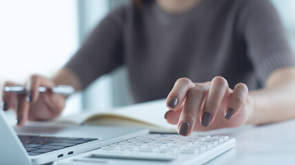 Plakat Close up woman using calculator to calculate home finance and writing note, accounting on table, budget management. budgeting and tax calculation