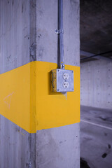 Industrial electrical outlet on yellow striped concrete pillar