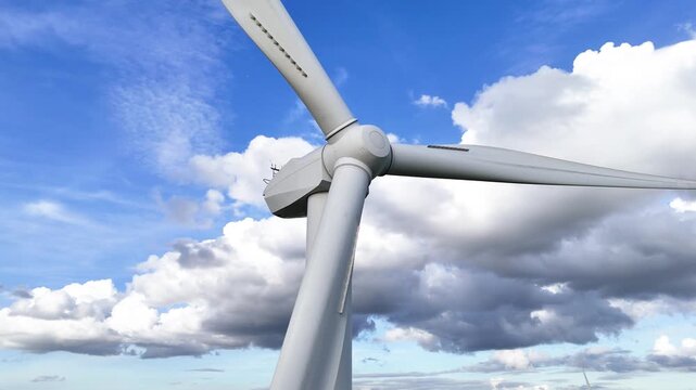 low perspective wind turbine three blades extending central hub against deep blue sky billowing clouds enhancing sense height from long wide angle low-angle 