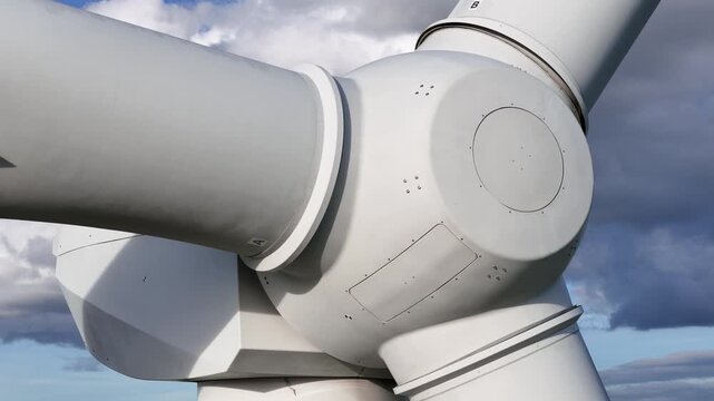 wind turbine aerodynamic hub blades under heavy textured clouds mechanical strength elegance structure close upward angled shot angle engineering renewable energy design 
