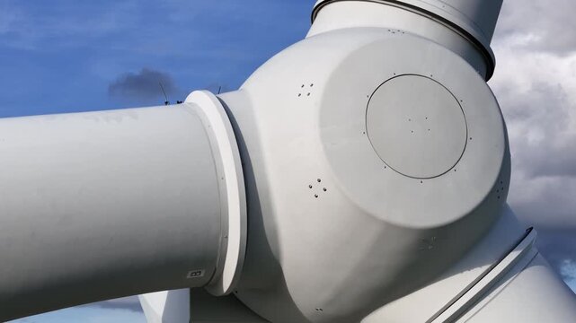 low high res wind turbine rounded hub housing access panel sensor mast blade connections against bright cumulus clouds clean electricity engineering reveals angle view structure 