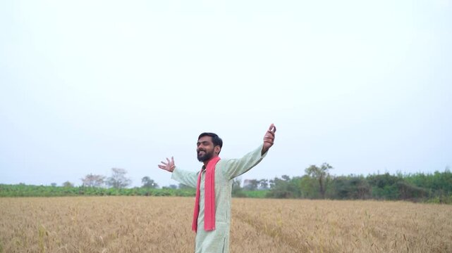 Young indian farmer standing at wheat agriculture field	