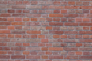 Obraz premium Textured red brick wall with varying shades and sizes of bricks, showcasing a rustic and aged appearance suitable for architectural backgrounds or design projects