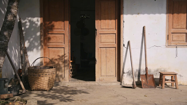 Rustic tools and basket outside old house doorway with wooden shutters
