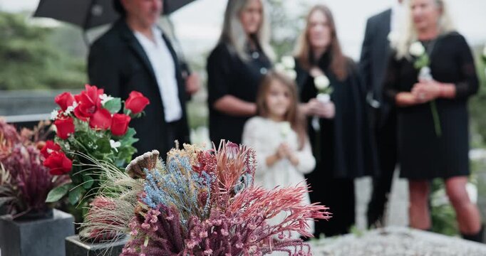Flowers, family and funeral by tomb at cemetery, graveyard or outdoor for farewell or burial. Child, people and group together for grief, death and respect with bouquet for eulogy, mourning and loss