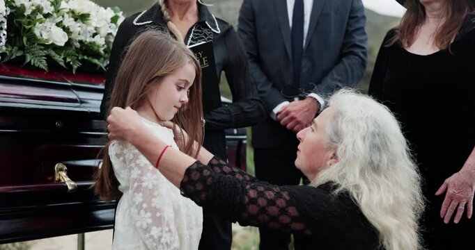 Child, sympathy and senior woman by coffin for funeral at cemetery, graveyard or outdoor for farewell. People, orphan or family together for grief, death and respect or support with condolences