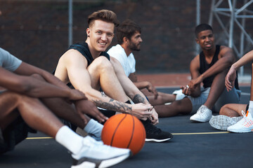 Fototapeta premium Basketball court, portrait and man with team, break or preparing for competition, happy and fitness. Outdoor, athlete and friends with strategy for match, smile and getting ready for sport tournament