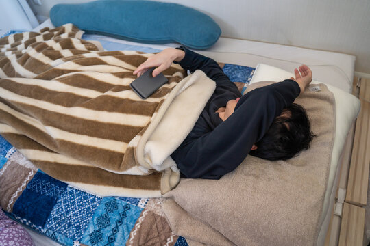 朝、布団で仰向けで眠る男性