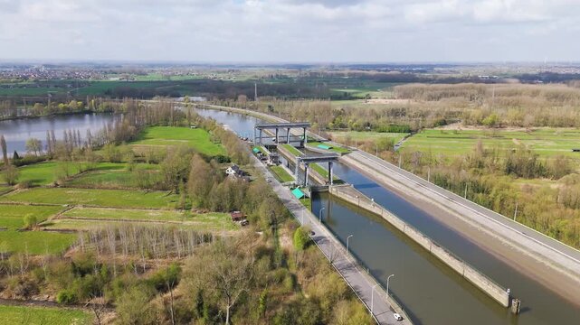 river lock complex cutting through vibrant fields woods twin steel framed gates quiet service roads by water rural landscape fading into horizon reveals drone shot broad 