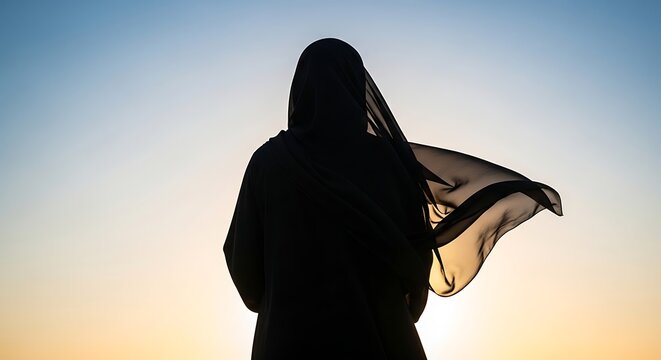 Silhouette of a woman wearing a hijab against a sunset sky, symbolizing peace and reflection