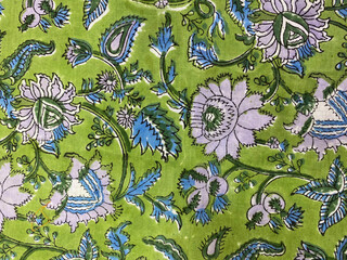 A close-up view of traditional hand block printed cotton fabric featuring a vibrant lime green floral pattern. © blendindia