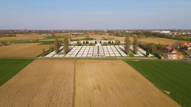 tyne cot cemetery appears pristine white rectangle amid vast tan green fields grid headstones central memorial structures create serene geometric pattern across wwi zonnebeke belgium 