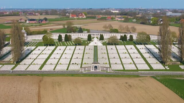 tyne cot cemetery forms luminous white grid enclosed by curved memorial wall flanked tall poplars central cross sacrifice aligned along green avenue patchwork tan fields wwi zonnebeke 