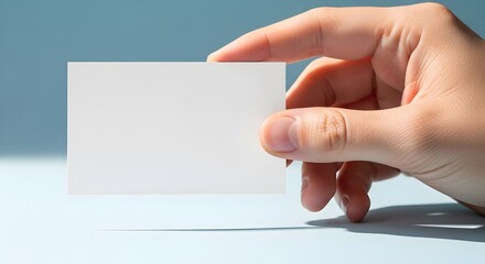 Obraz premium Hand holding blank white business card on blue background