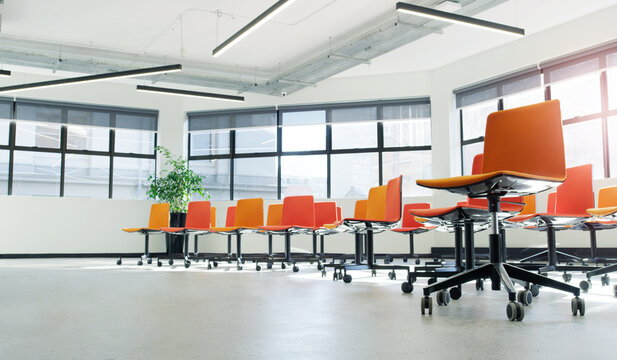 Chairs, conference or tradeshow with empty room for convention, presentation or business lecture. Low angle, interior and orange seats with furniture or layout for workshop, seminar or meeting venue