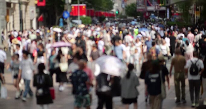 Blurred slow-motion view of anonymous crowd on Nanjing Road Pedestrian Street in Shanghai. Daytime shot captures immense scale of people walking along bustling alley during major Chinese holiday