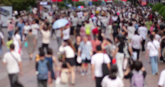 Defocused lengthwise slow motion view on pedestrian street full of walking people at hot day. Big Chinese city shopping district at holiday time, overhead perspective