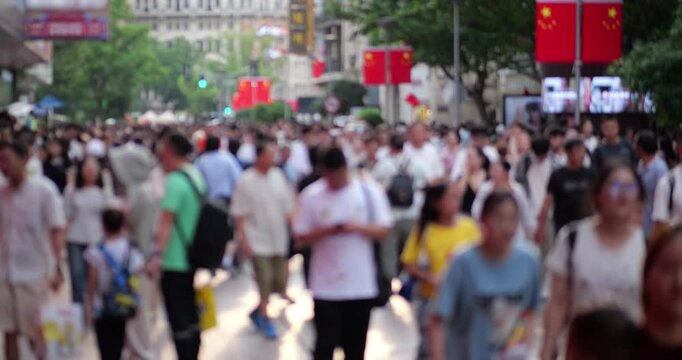 Defocused slow motion shot of massive crowd of anonymous people walking down busy pedestrian street of Shanghai city during National Day golden week. Shopping alley full of people
