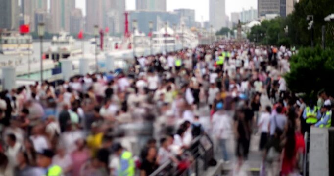 Large, out of focus crowd of unrecognizable people rushing along busy waterfront promenade, time-lapse shot in day time. Overhead view with diminishing perspective shows straight embankment.