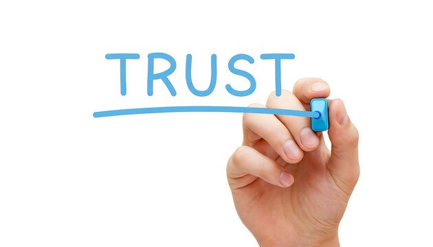 A hand using a blue marker to underline the word trust written on a clean white background surface