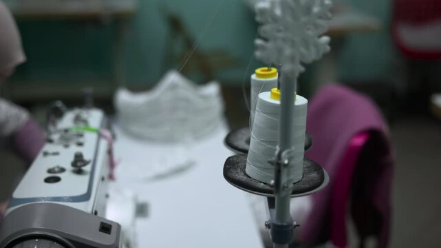 Concentrated Spools And Bobbins Foreground Contrasted By Busy Workshop With Machinery In Background. Media